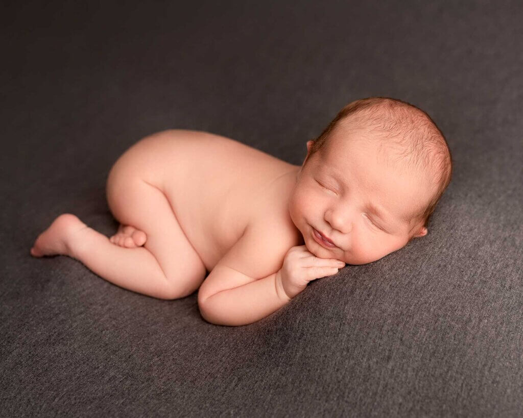 newborn baby boy sleeping in a tushy up pose in a newborn belfast photoshoot