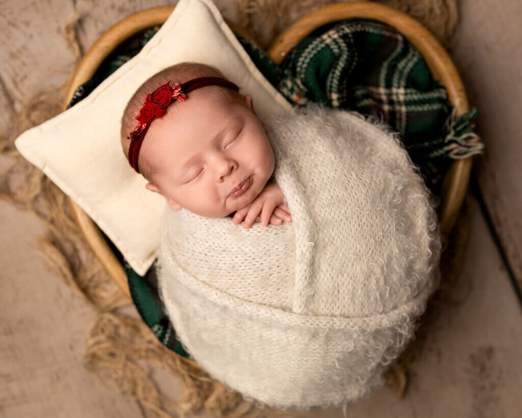 baby girl wrapped up and sleeping in a heart box by the best newborn photographer in Belfast