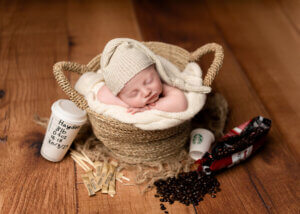 baby in a basket with a coffee cup by the the best newborn photographer in Belfast