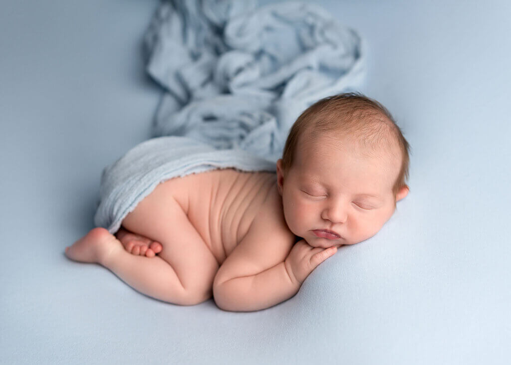 sleeping baby lying on their tummy with a blanket over their bottom by the best newborn photographer in Belfast